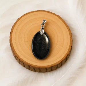 Pendentif Obsidienne dorée noir et doré présenté sur un rondin de bois