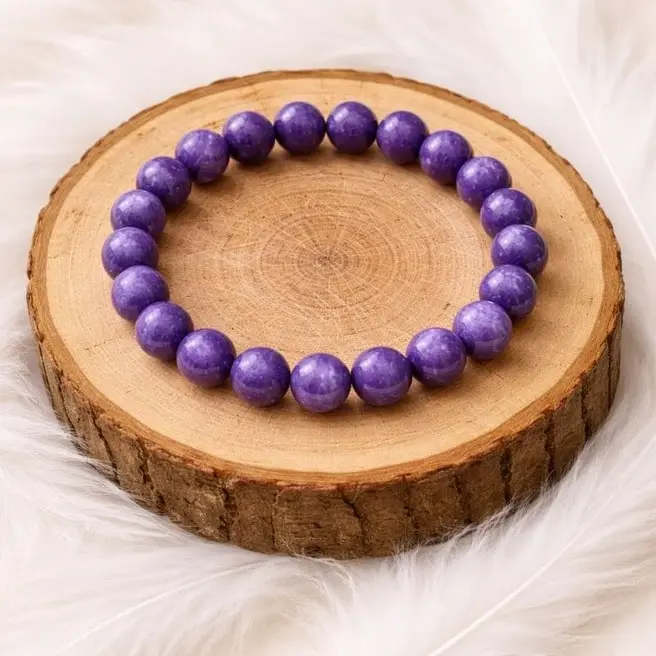 Bracelet lépidolite en pierres naturelles violettes posé sur rondin en bois