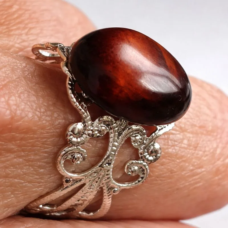 Bague réglable œil de taureau portée au doigt, pierre naturelle ovale marron rouge