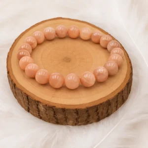 Bracelet pierre de lune pêche 8mm posé sur rondin en bois