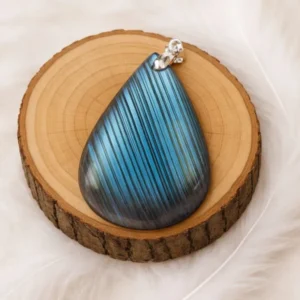 Pendentif en labradorite bleue en forme de goutte posé sur un rondin de bois