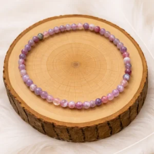 Bracelet en tourmaline rose et eudialyte présenté sur un rondin de bois naturel