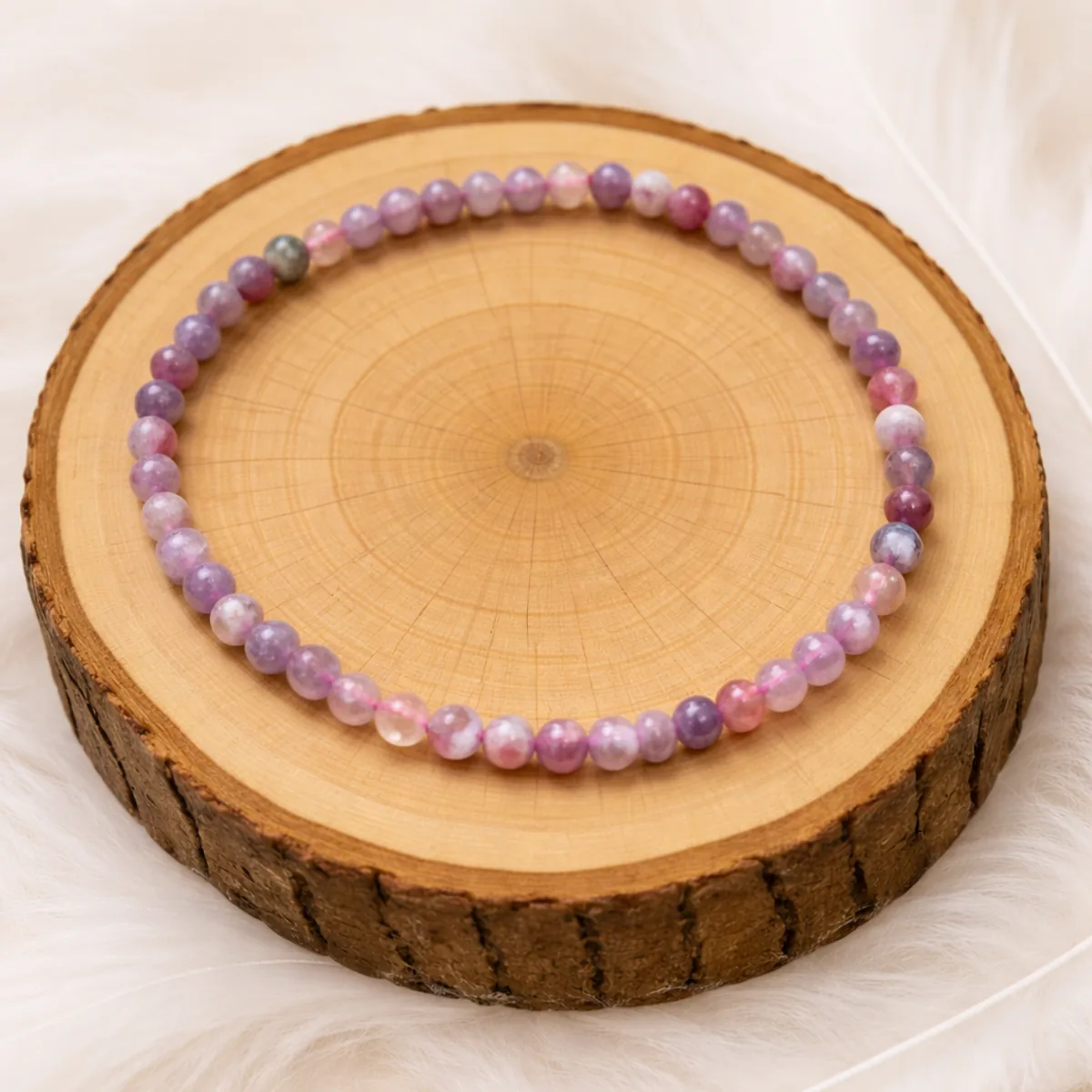 Bracelet en tourmaline rose et eudialyte présenté sur un rondin de bois naturel