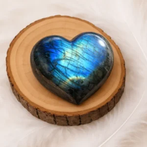 Cœur en labradorite poli aux reflets bleus posé sur un rondin de bois naturel