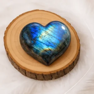 Cœur en labradorite poli n°3 aux reflets bleus posé sur un rondin de bois naturel