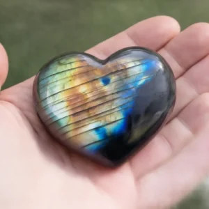 Cœur en labradorite poli n°4 tenu dans une main avec reflets multicolores