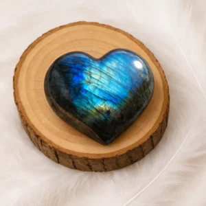 Cœur en labradorite poli aux reflets bleus posé sur un rondin de bois naturel