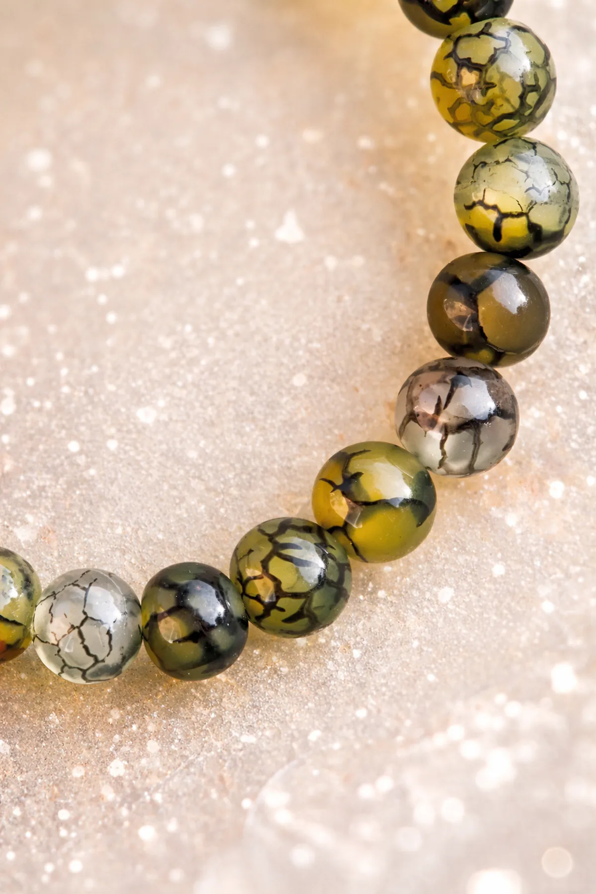 Détail des perles du bracelet en agate veine de dragon sur fond lumineux