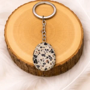 Porte-clés en jaspe dalmatien pierre naturelle posé sur rondin en bois