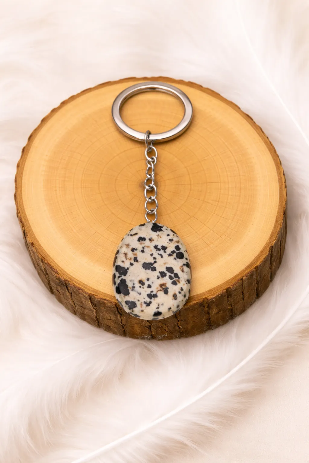 Porte-clés en jaspe dalmatien pierre naturelle posé sur rondin en bois