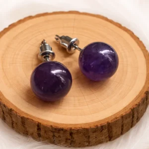Boucles d’oreilles en améthyste naturelle violette posées sur un rondin de bois