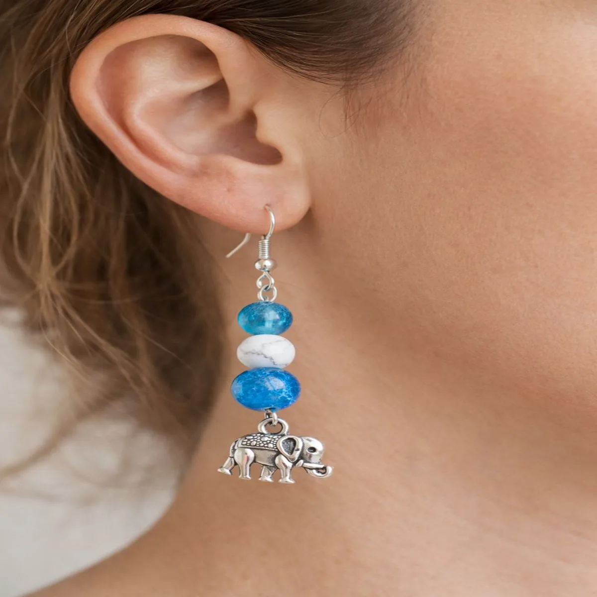 Boucles d’oreilles apatite et howlite portées à l’oreille avec pendentif éléphant