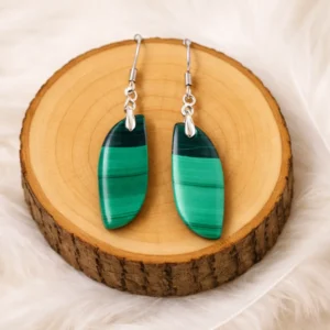 Boucles d’oreilles en malachite naturelle verte aux motifs striés, présentées sur un rondin en bois