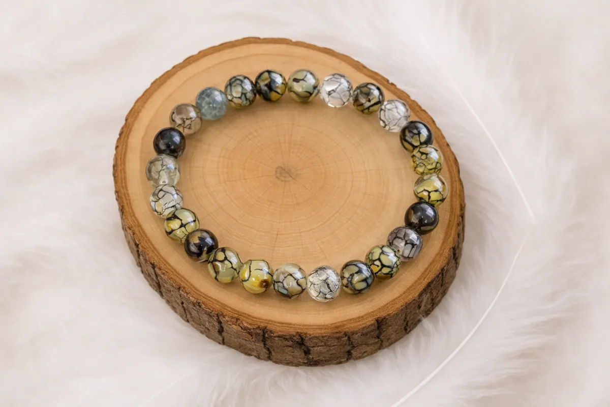 Bracelet en agate veine de dragon aux perles vertes et jaunes posé sur une pierre naturelle