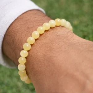 Bracelet en calcite jaune porté au poignet, perles rondes jaunes sur fond extérieur flou.