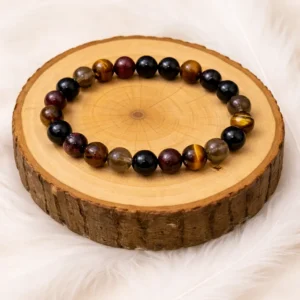 Bracelet chance et protection en œil de tigre, grenat, tourmaline noire et quartz fumé posé sur rondin de bois