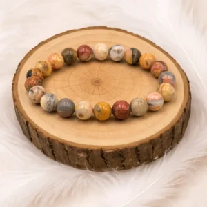 Bracelet pierre crazy lace naturelle aux tons chauds présenté bien rond sur un rondin en bois