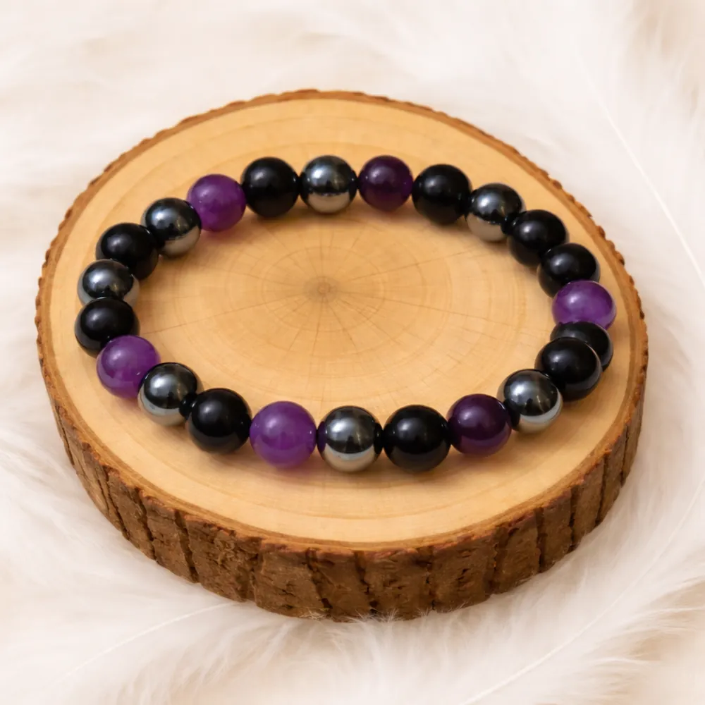Bracelet en perles améthyste, hématite et tourmaline posé sur un rondin en bois