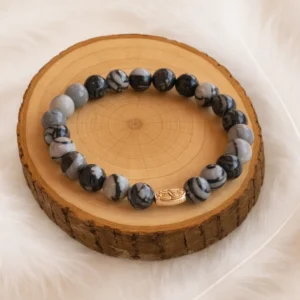 Bracelet en jaspe toile d’araignée naturel posé sur un rondin en bois