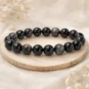 Bracelet en obsidienne argentée posé sur un rondin de bois clair