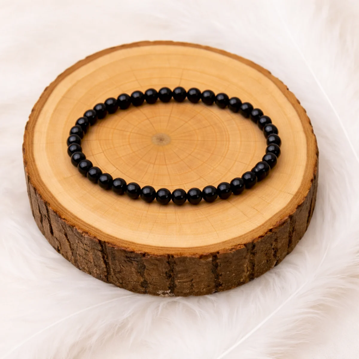 Bracelet en onyx noir 6 mm posé sur rondin en bois