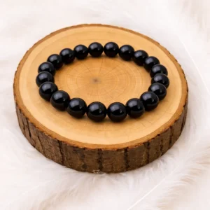 Bracelet en onyx noir 8 mm posé sur rondin en bois naturel