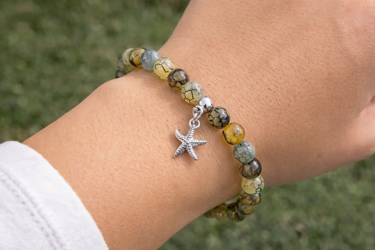 Bracelet en agate veine de dragon aux perles vertes et jaunes porté au poignet avec breloque étoile