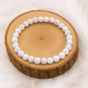 Bracelet en howlite blanche 6 mm présenté sur rondin en bois