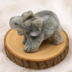 Éléphant en labradorite sculpté posé sur un rondin en bois