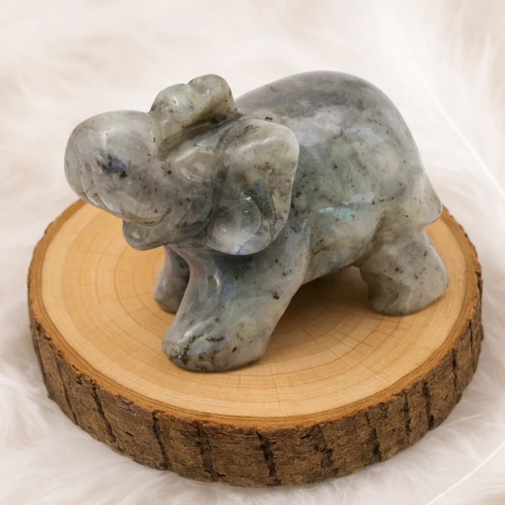 Éléphant en labradorite sculpté posé sur un rondin en bois