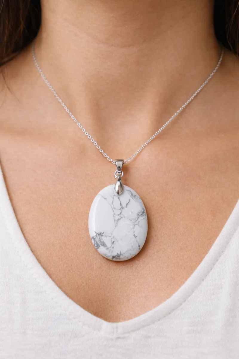 Pendentif en howlite blanche porté au cou, pierre naturelle veinée grise.