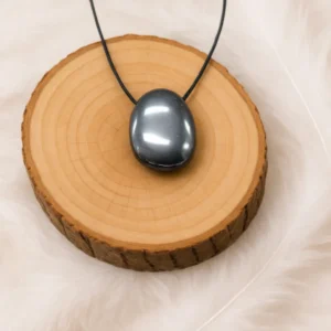 Pendentif en hématite roulée présenté sur rondin en bois naturel