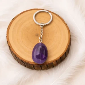 Porte-clés en améthyste naturelle violet posé sur un rondin en bois