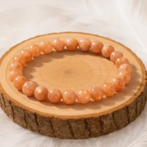 Bracelet pierre de soleil en perles naturelles orange, présenté sur un rondin en bois
