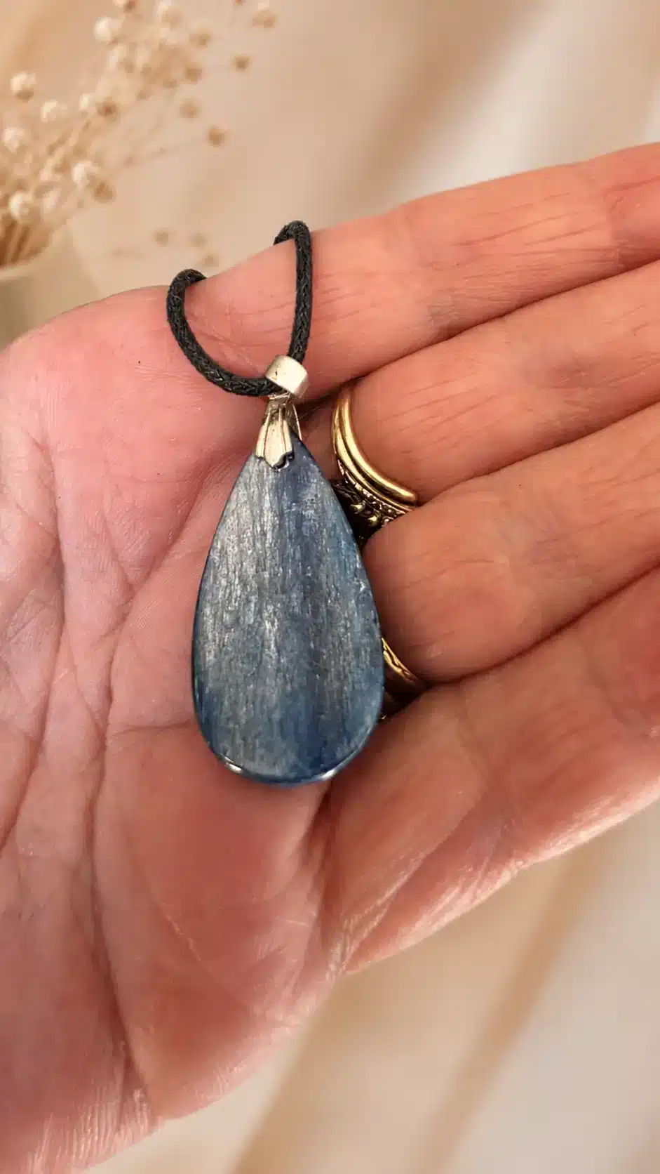 Dos du pendentif en cyanite naturelle présenté dans une main