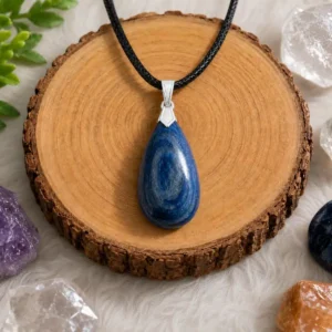 Pendentif en cyanite bleue avec bélière argentée présenté sur un rondin en bois