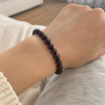 Bracelet en grenat naturel porté au poignet dans une ambiance douce et naturelle à la maison