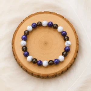 Bracelet burn-out en Lépidolite, Howlite et Quartz fumé présenté sur un rondin en bois