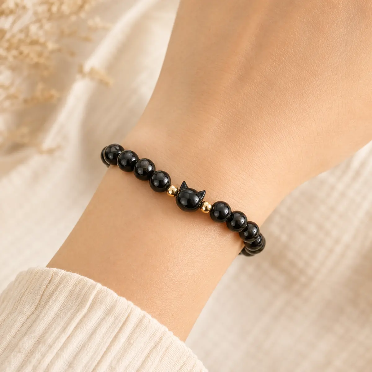 Bracelet en obsidienne dorée 8 mm avec perle tête de chat porté au poignet