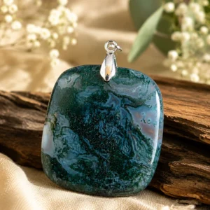 Pendentif en agate mousse carré de 30 mm présenté sur un fond naturel avec bois et fleurs blanches