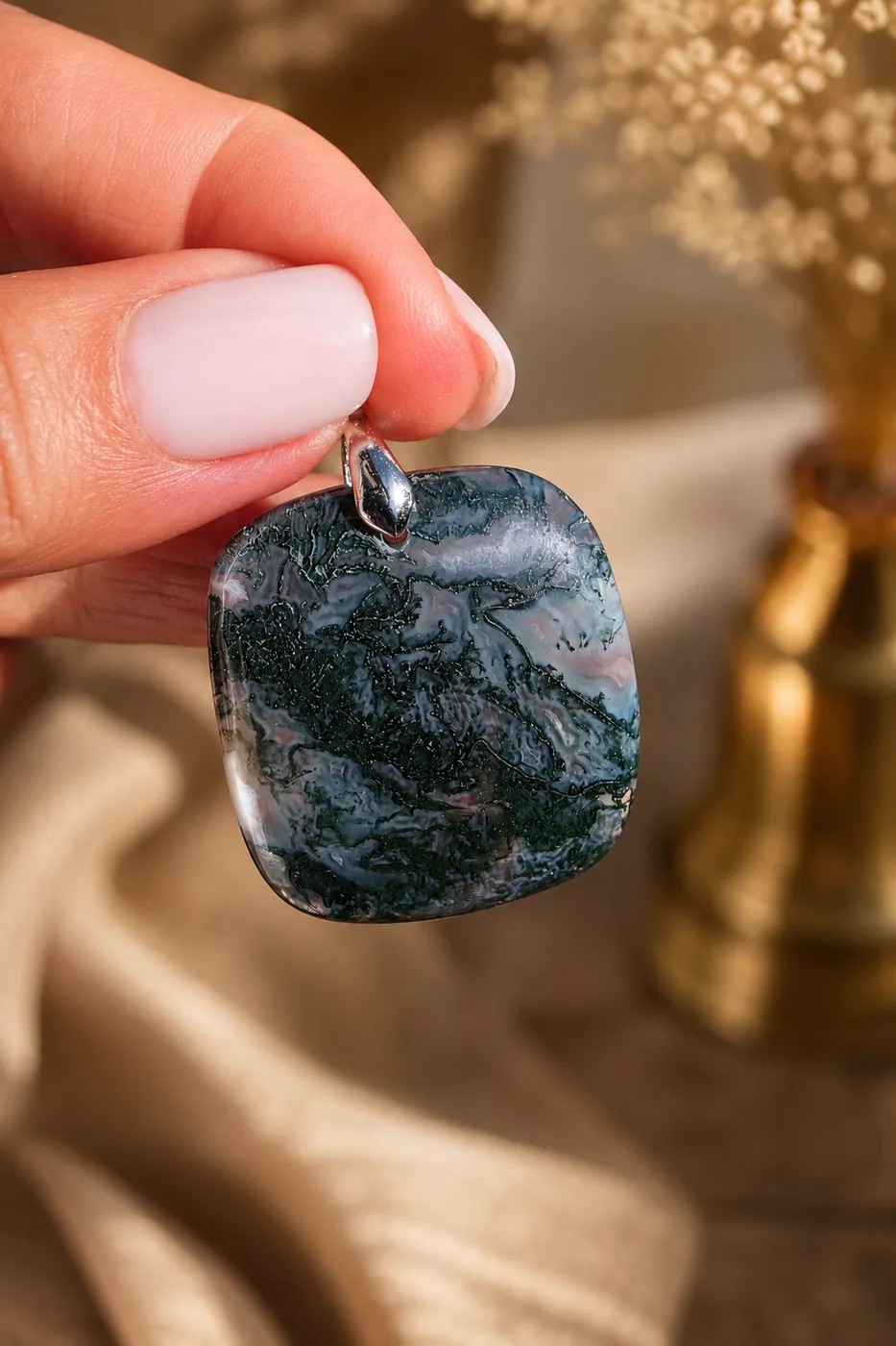 Pendentif carré en agate mousse naturelle de 30 mm tenu à la main sur un fond beige lumineux