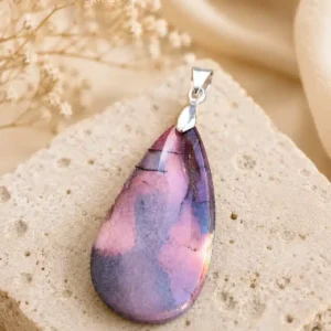 Pendentif en Jaspe Mokaïte naturel en forme de goutte posé sur un support en pierre