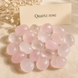 Pierre roulée en quartz rose pâle sur fond beige avec fleurs séchées