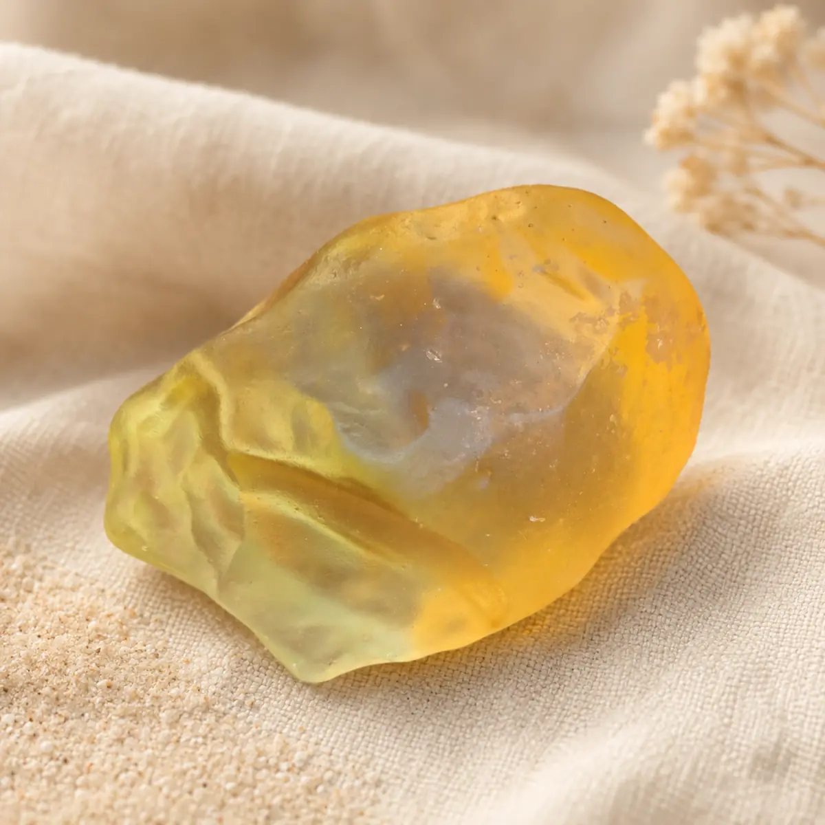 Verre libyque naturel brut jaune doré posé sur un fond en lin beige