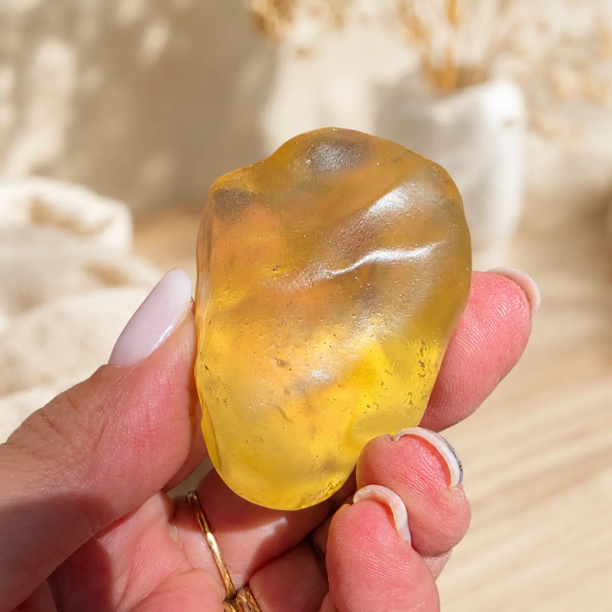 Gros plan d’un verre libyque jaune doré tenu en main sur un fond clair