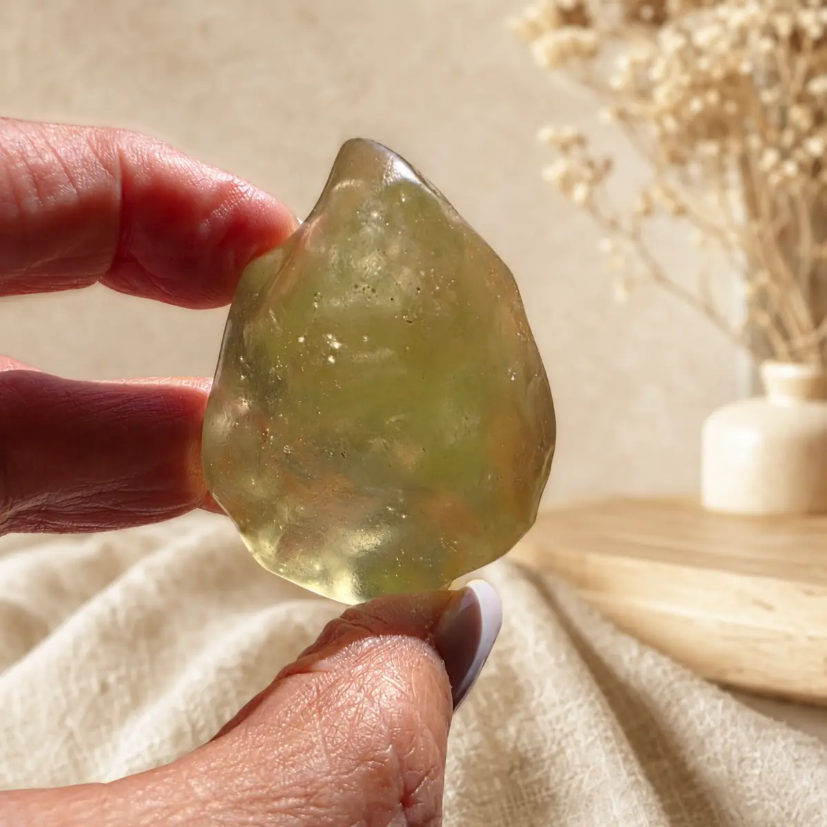 Verre libyque naturel translucide en forme de pointe tenu entre les doigts